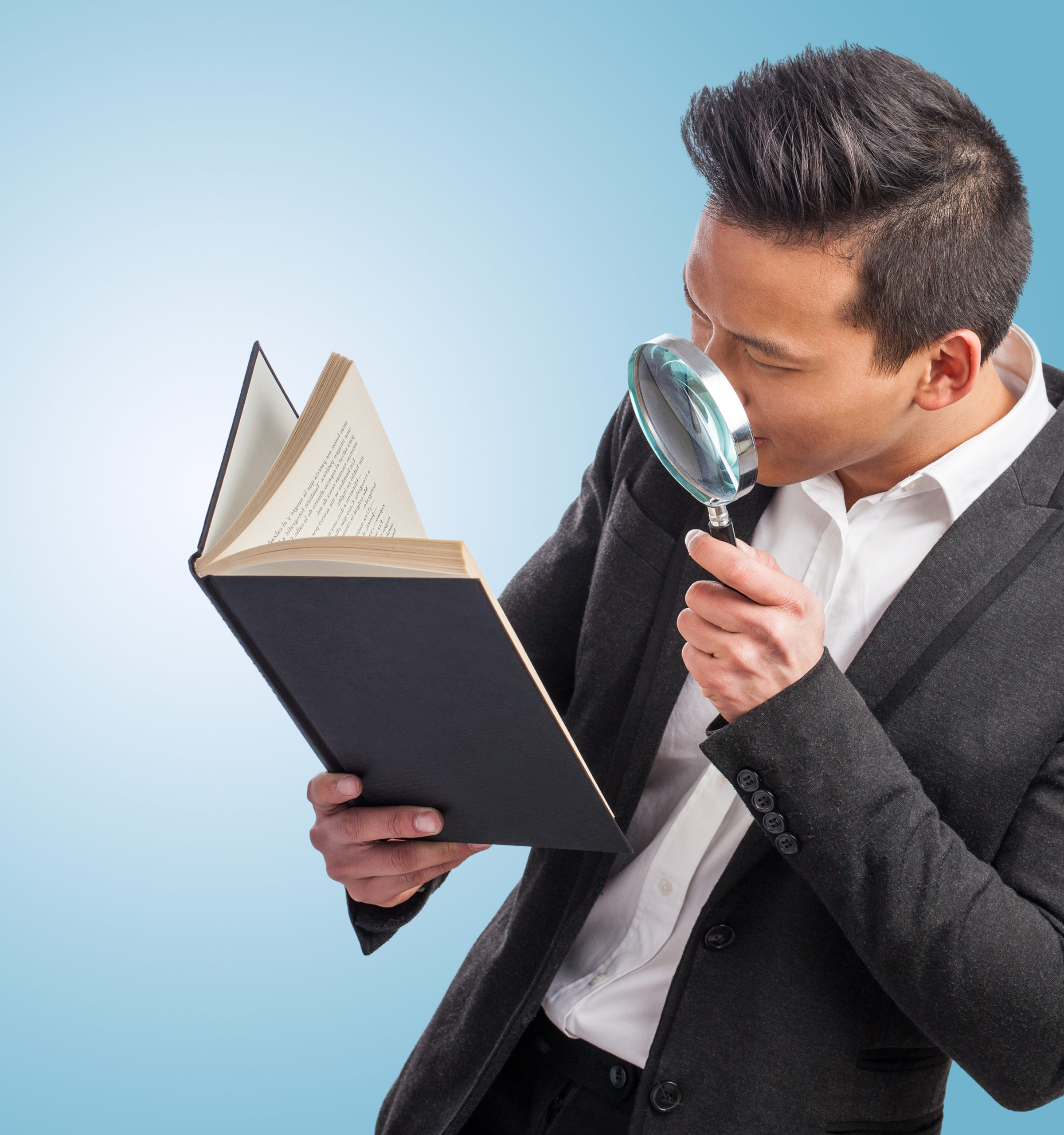 Person examining a book with magnifying glass